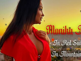 Monika Fox looks stunning in her red suit as she poses in the mountains.